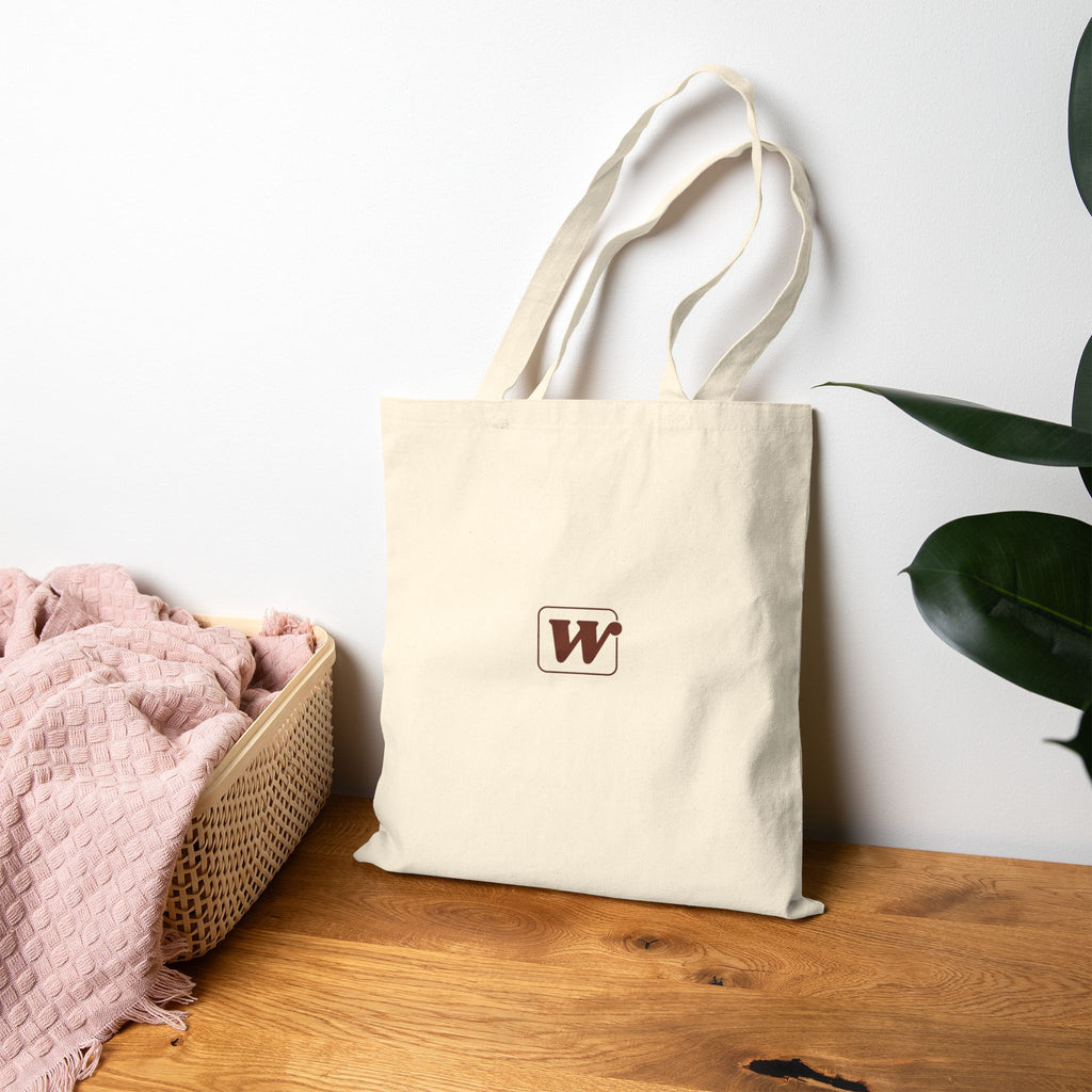 Canvas tote bag featuring an Espresso is served graphic with three clinking coffee mugs on the back and a front pocket W logo from The W-League collection