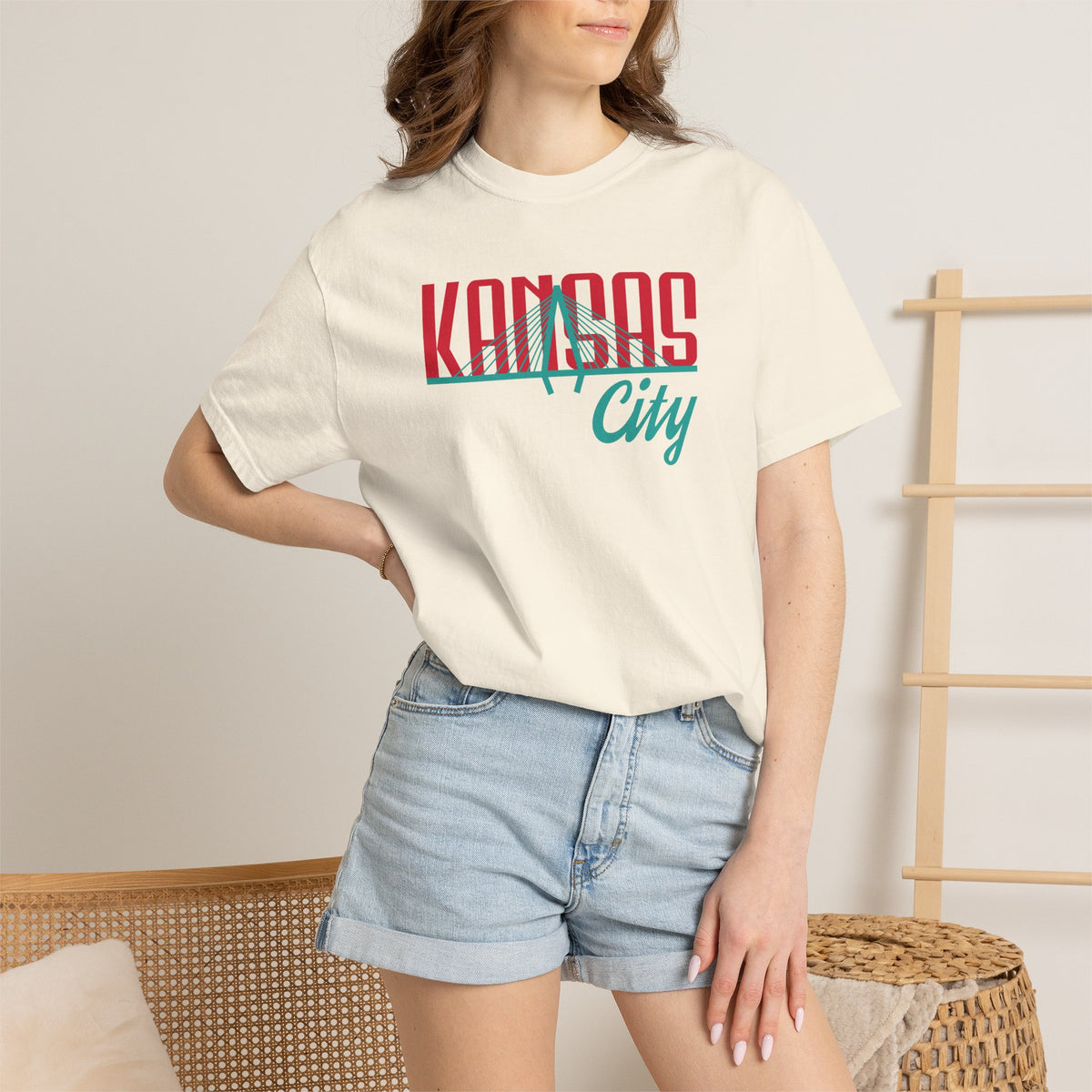 Ivory garment-dyed t-shirt front view featuring "Kansas City" with bridge graphic in red and teal retro script across the chest.