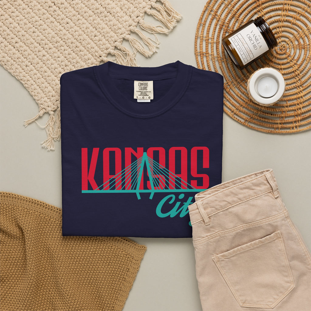 Navy garment-dyed t-shirt front view featuring "Kansas City" with bridge graphic in red and teal retro script across the chest.