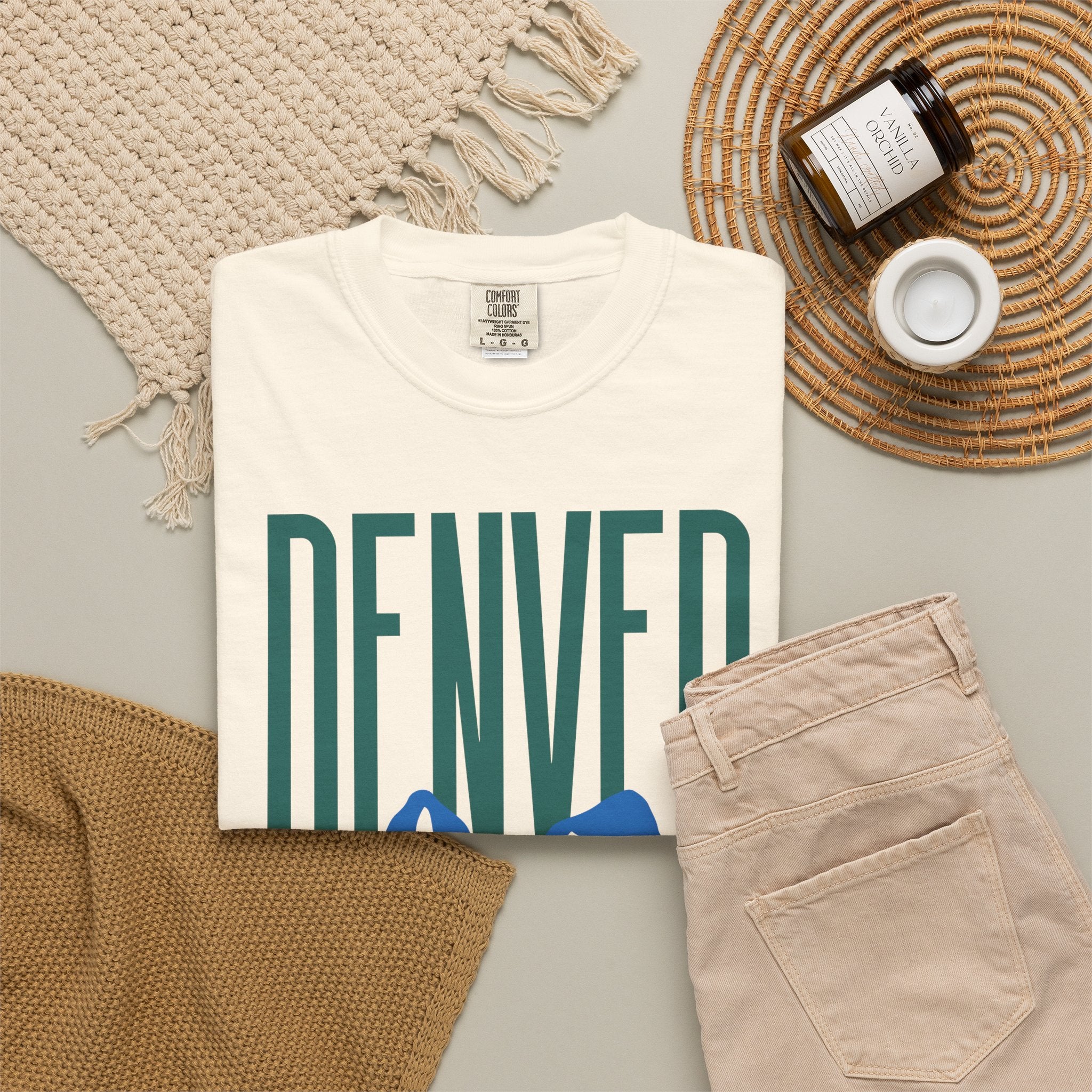 Ivory Denver mountain graphic t-shirt featuring block lettering above a blue Rocky Mountain silhouette, ideal for game day fan gear.